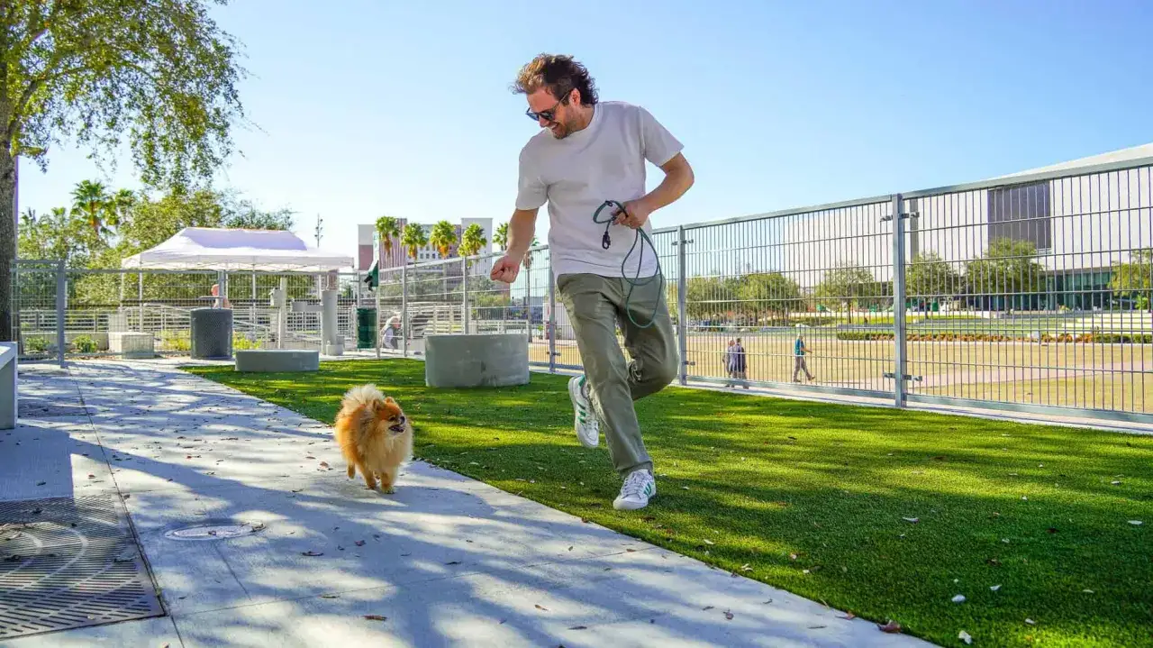 Un homme rit en courant avec son petit chien dans un parc. La question 